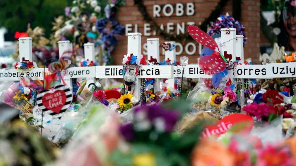 Flowers and other items surround crosses at a memorial