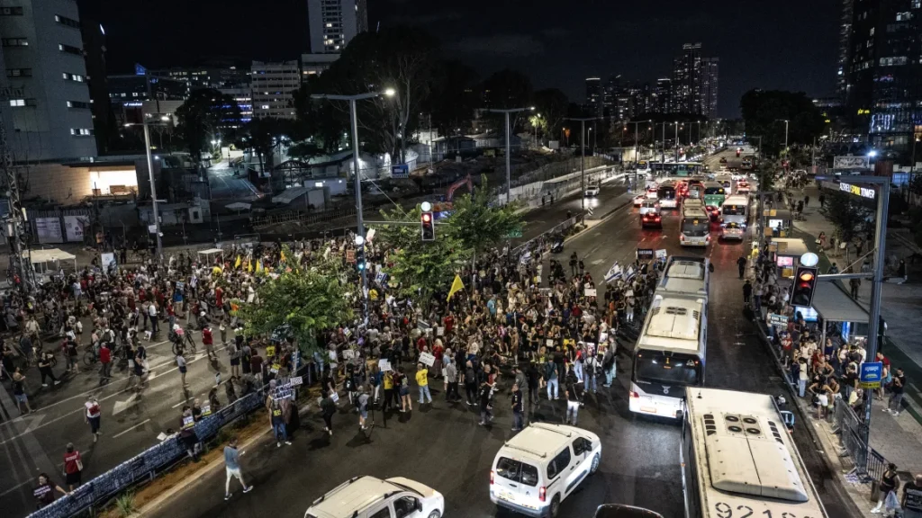 Israeli protesters holding banners and photos gather outside the defense ministry