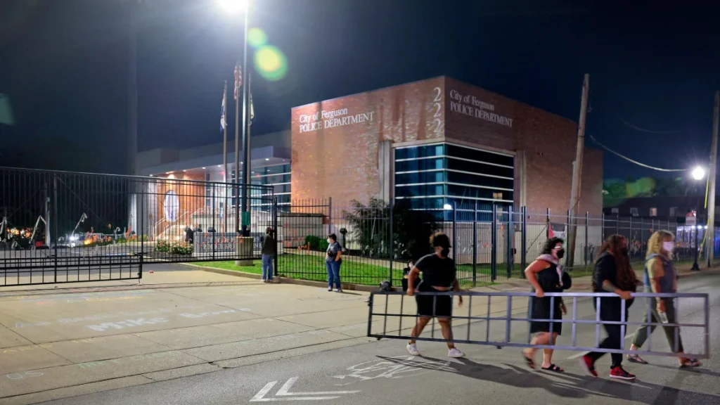 Protesters dismantle and remove a portion of a newly-installed gate outside the Ferguson